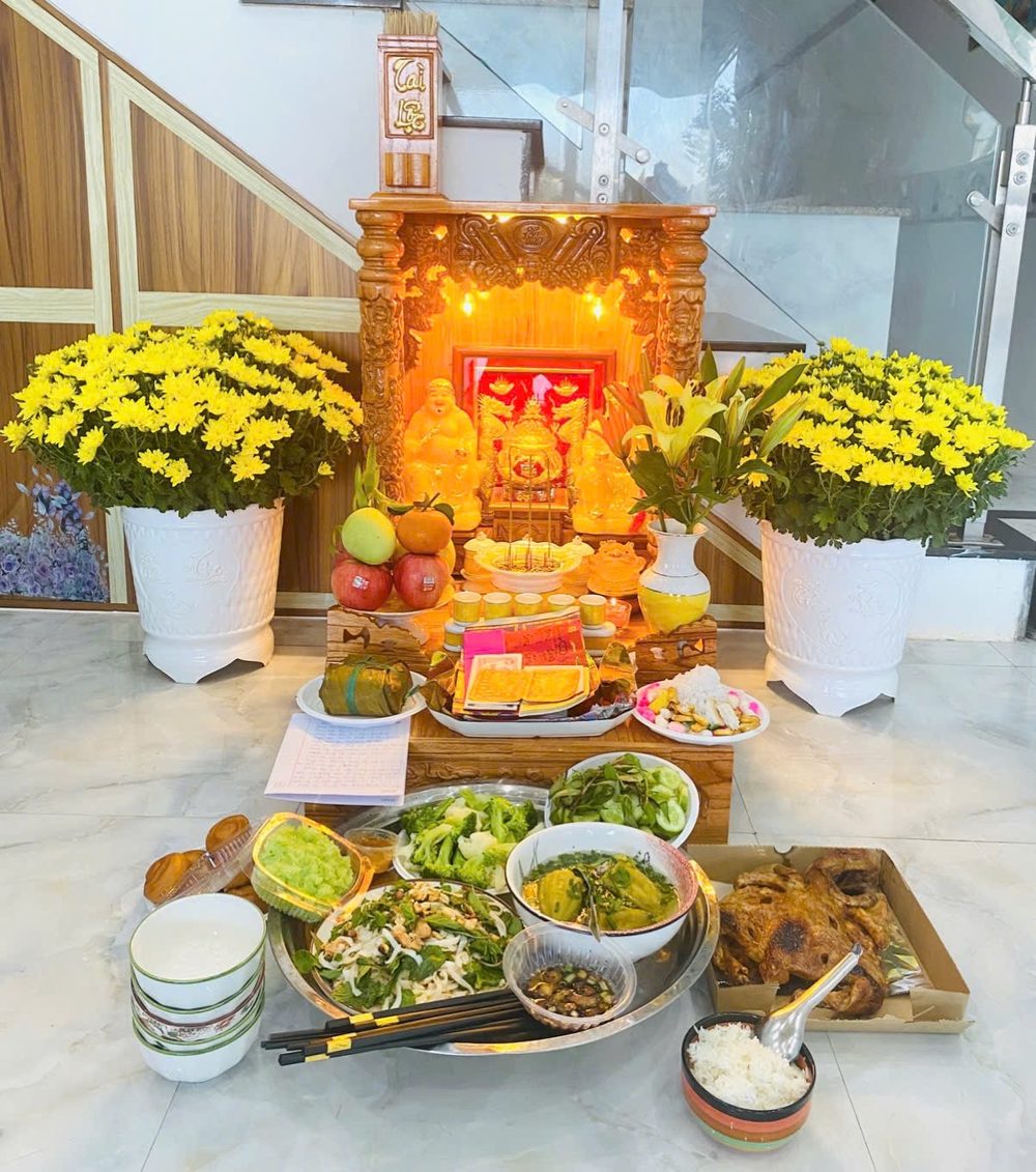 Bàn thờ Thần Tài Thổ Địa của một khách Tài Lộc, hoa cúc vàng hai bên và mâm cúng đầy đủ
