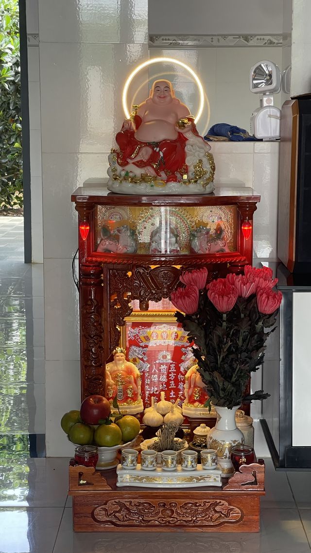 Bàn thờ Thần Tài của khách, hoa hồng đỏ bên cạnh